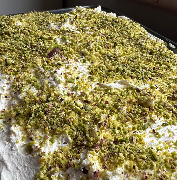 Cardamon & Pistachio Cheesecake Bars cut in squares sitting on parchment and big Rasmalai cake covered in thick whipped cream covered in ground pistachios