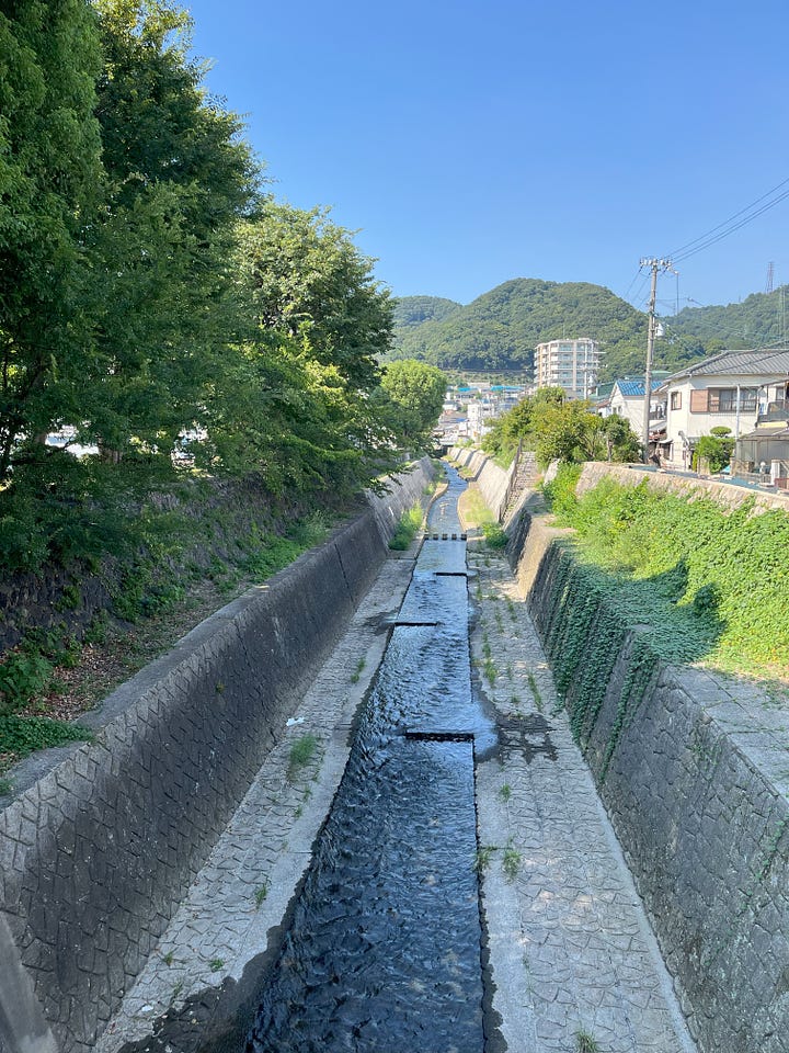 Pictures of the Minato River looking upstream and downstream. A concrete-lined channel in both directions, but the mountains are visible upstream.