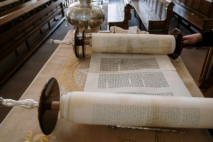 Left: open Torah scroll on reading table with silver crown behind; right, man with talis over his head in front of closed ark