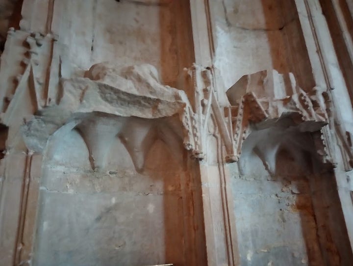 Bases of destroyed stone statuettes on wall above Hugh Despenser tomb