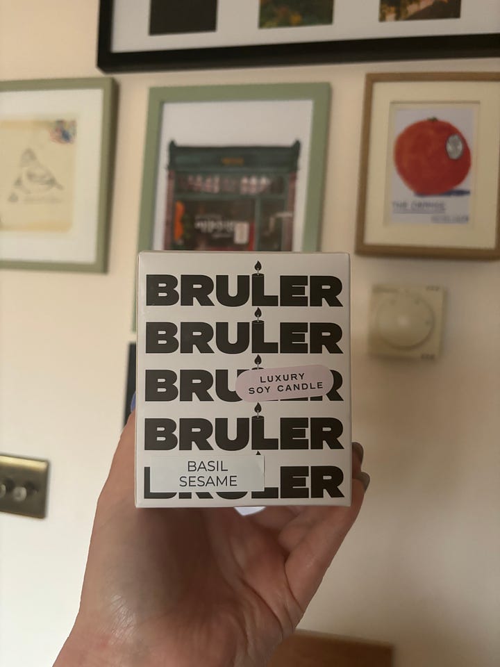 1. package with bold text reading BRULER BRULER BRULER BRULER BRULER. 2. big glass candle pot with green label reading BASIL SESAME in bold font.