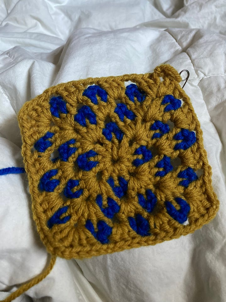medium ginger shiba inu curled up in cosy chair, a crochet project in blue and gold, a pile of yarn skeins on the bed, same dog sat at the top of the house steps from behind