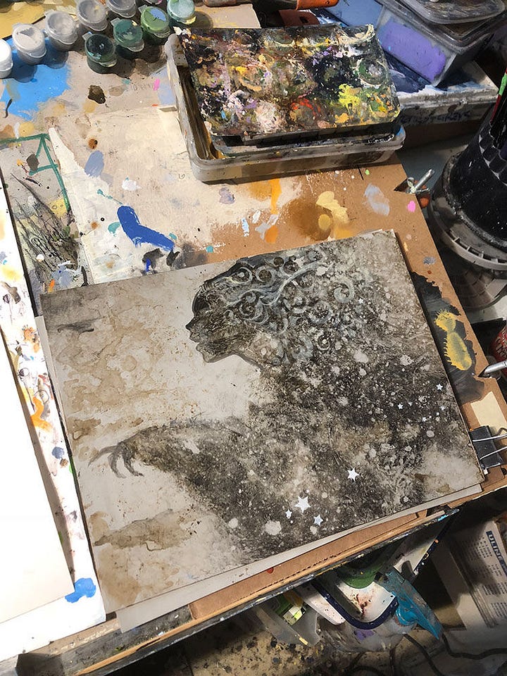 LEFT: An early photo of the figure in progress with the face defined in silhouette. Taken at an angle, the artist's illustration table occupies most of the photo. The space is a bit of a mess. This is how the sausage is made! RIGHT: Work in progress photo of STARCASTER. The figure is worked out in detail in raw umber on black. Her eyes focus on overlapping bubbles of light evoked by an elegant gesture. Fingers thrown wide, a soft glow illuminates the back of her hand in silhouette. In her other hand, she daintily pinches a tiny ornate vial by its long neck. Vapors trailing off the tincture waft low in a zig-zag motion. Her hair is held back by an ornamented headdress of swirls and stars that give way to ringed planets and spiral galaxies.