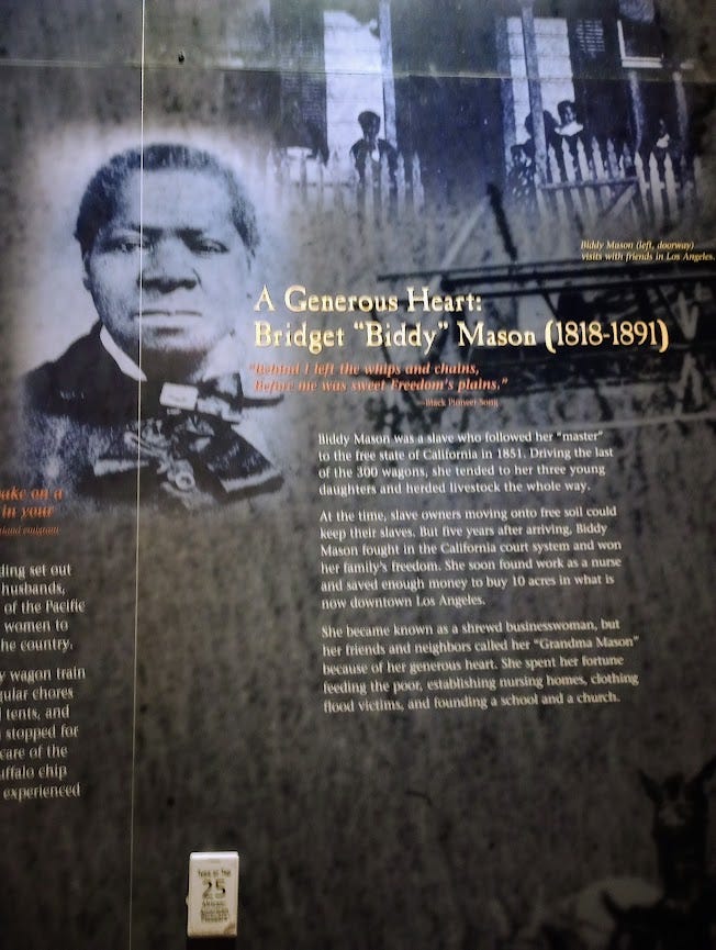 Room with panels showing large photos of Native, Black, and white people and lots of text. Panel showing Biddy Mason, who traveled fro the Deep South to Utah and then Los Angeles, as a slave. She sued and won her freedom in LA. Image: Annette Laing, 2024