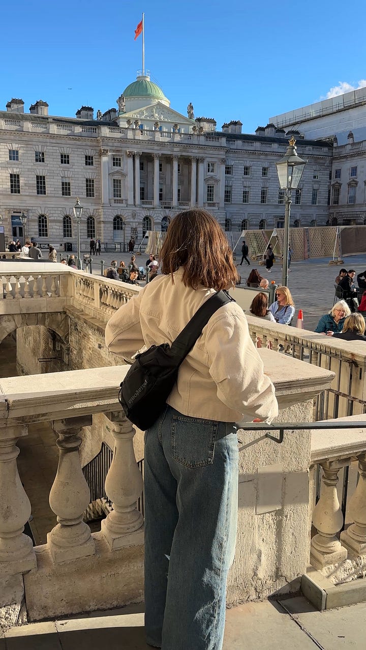 On the left, Lucy wears Carhartt stripe denim overshirt. On the right, Lucy stands in front of a green wall wearing a vintage beige golf jacket, green Sezane cardigan and white COS tee..