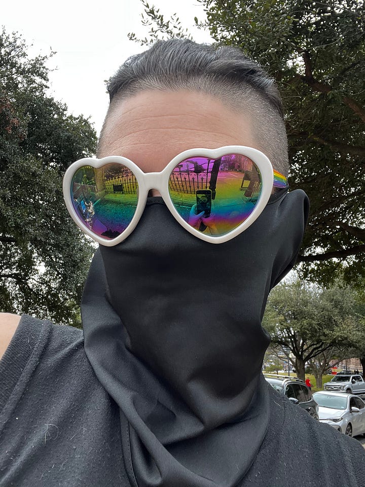 Lyric, with a black face mask, black shirt, and white heart rainbow glasses