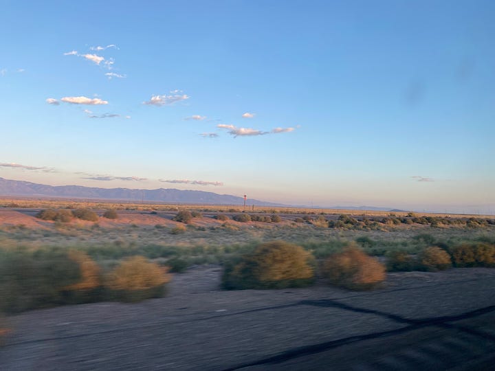 Four images: purple mountains with a tinge of sunset color below a blue sky, a tabby cat voguing on top of a fence post, four chickens in a coop and three eggs in a hand, and a real good kitty on top of an awning like a tiny god with clouds behind her