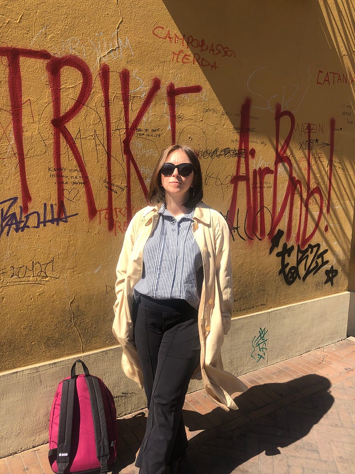 Rebecca stands in front of a graffiti-covered wall in her go-to bad day outfit, unsmiling.