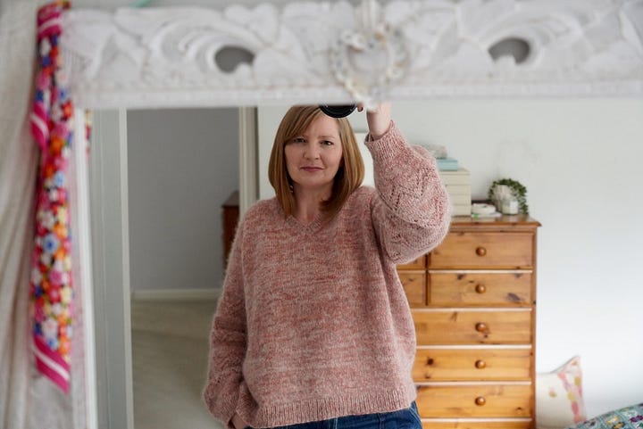 A woman wearing her hand knitted pink Peak Sweater