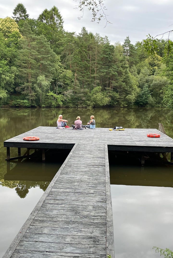 Books and three ladies sitting my a lake