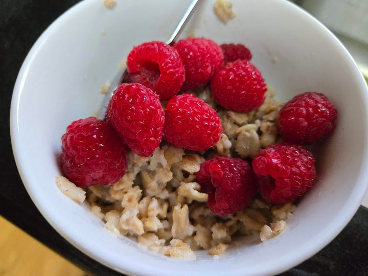 Left, oatmeal with meyer lemon marmalade on top.  Right, oatmeal with raspberries.  Both in white bowls.