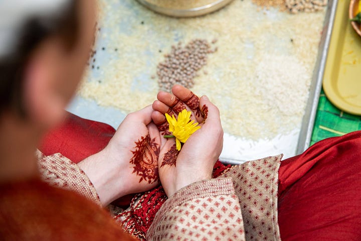 The bride's and groom's hands cup yellow flowers.