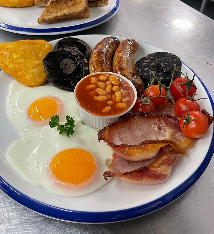 Eggs, bacon, beans, suasage etc on a plate and a cup of coffee