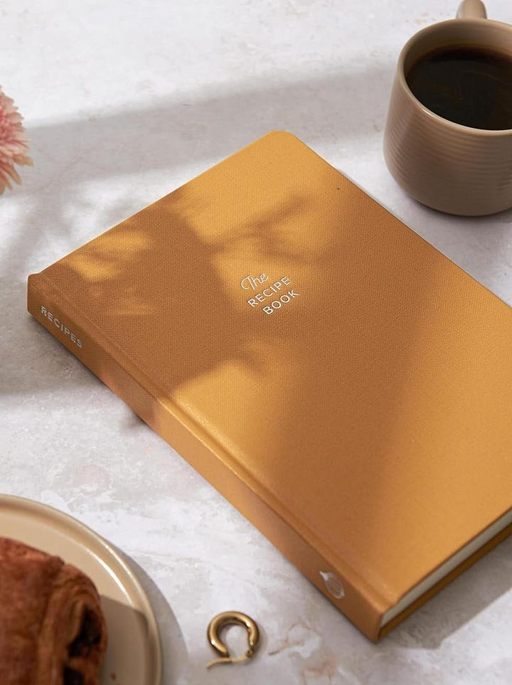 From left: a yellow recipe journal and a painted ceramic pitcher of olive oil.