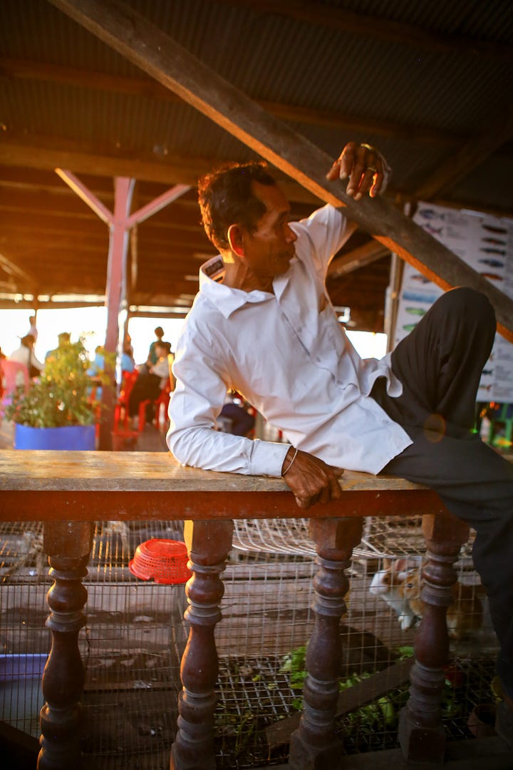 Various images from a day of photograph at Tongle Sap, including a man in a motorcycle helmet pointing, a boat in a river beside stilt houses, some kind of racoon animal in a cage, local children torturing shrimp, a man sitting on a railing, a young girl looking bored while trying to sell beer, and two men standing on a wall over a huge crocodile.