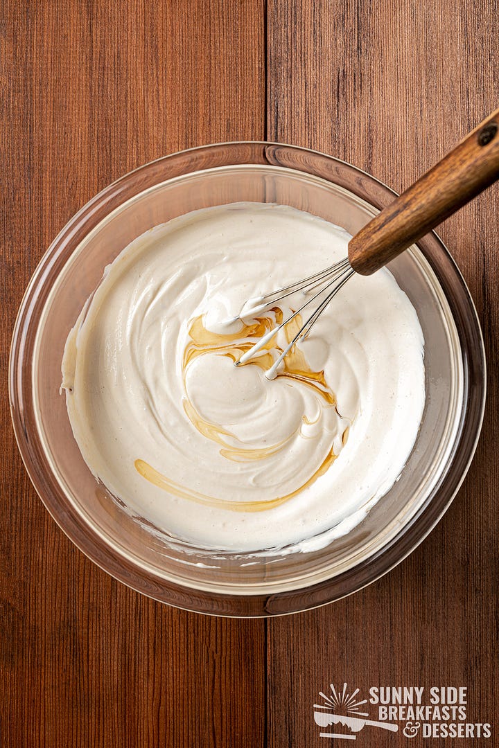 Mixing Greek yogurt in a glass bowl.