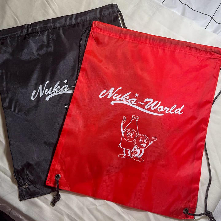 Red and black drawstring bags with Nuka World and picture of Bottle and Cappy