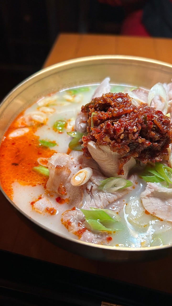 Pork gukbap topped with scallions and chili crisp. The full spread of gukbap bowls, kkakdugi (radish kimchi), and sides of fresh ginger and garlic.