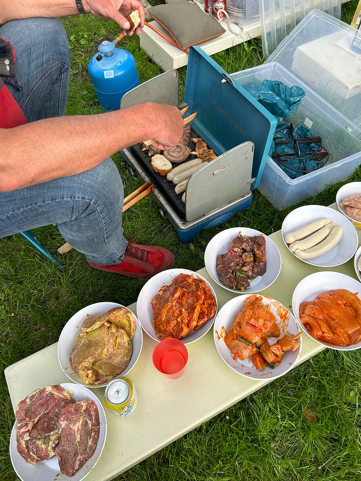 Karen Bussen gives the thumbs up on a sailboat. A man barbecues meat on a small camping stove.