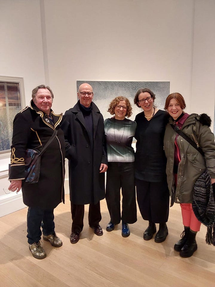 a group of people gathered in an art gallery, all smiling