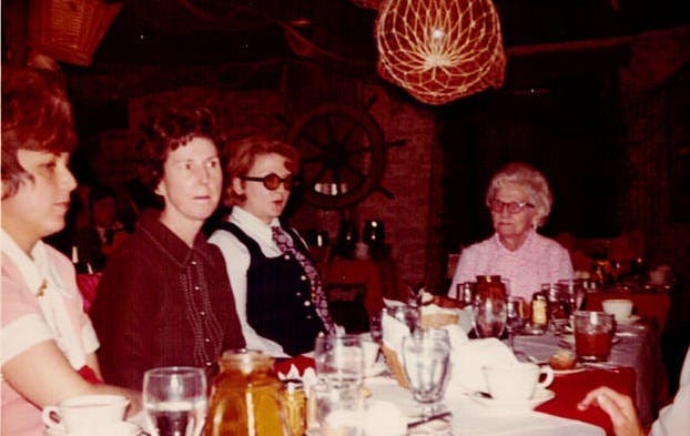 Four old photos. One shows a teenage girl sewing. She is slim, with reddish hair, and is wearing a striped tee shirt. The other three photos show eight women (one with gray hair, the rest dark haired) smiling and posing for their pictures around a very 1970s restaurant table, complete with amber colored candle holders.