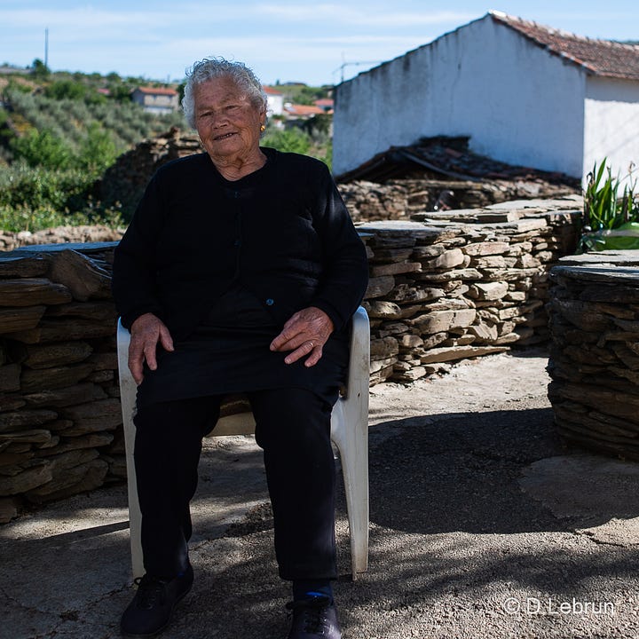 The photo shows an elderly woman in a small village in Portugal, 2023