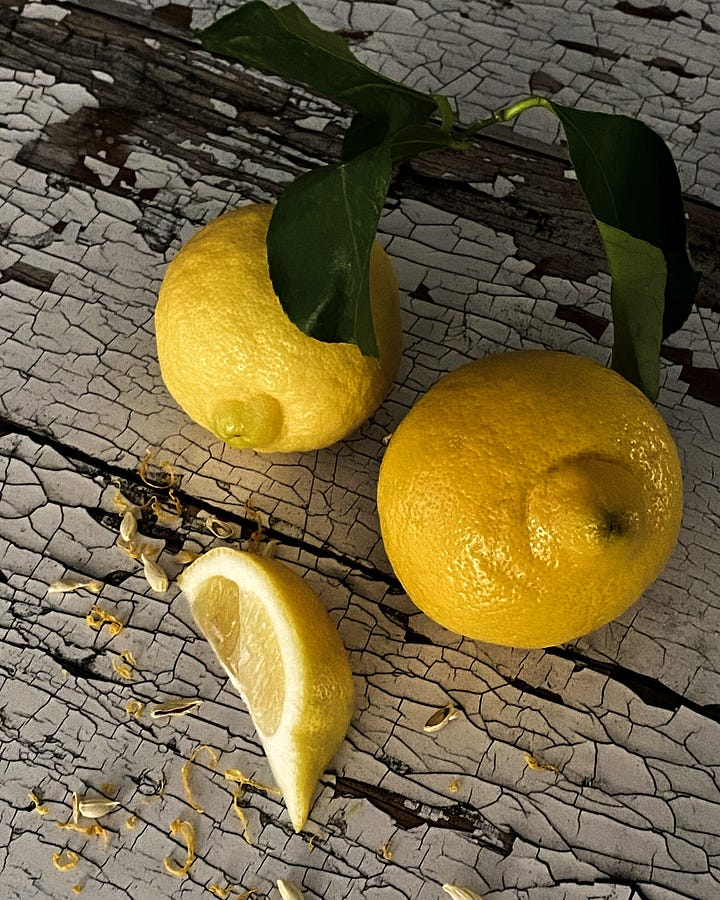 Overhead view of whole and quartered lemons on crusty white painted table