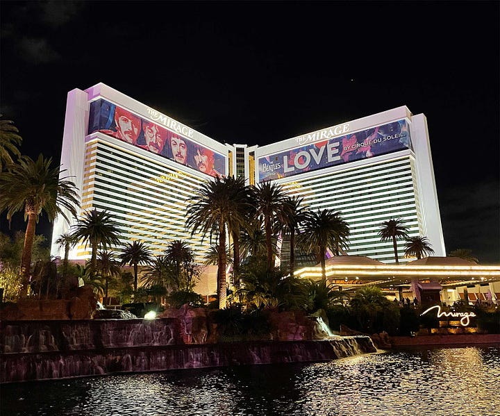 Exterior of Mirage Hotel tower and image of volcano feature erupting on Vegas strip.