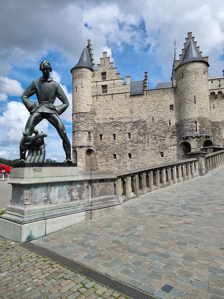 Photo 1: Fort Het Seen in the background with a statue of Lange Wrapper (a water spirit) towering over humans in the foreground. Photo 2: Antwerp Town Hall and statue of Brabo in the foreground throwing a severed hand. Photo 3: Photo from inside the Antwerp Bourse. Photo 4: Dave going down the wooden escalator in the St Anna tunnel. 