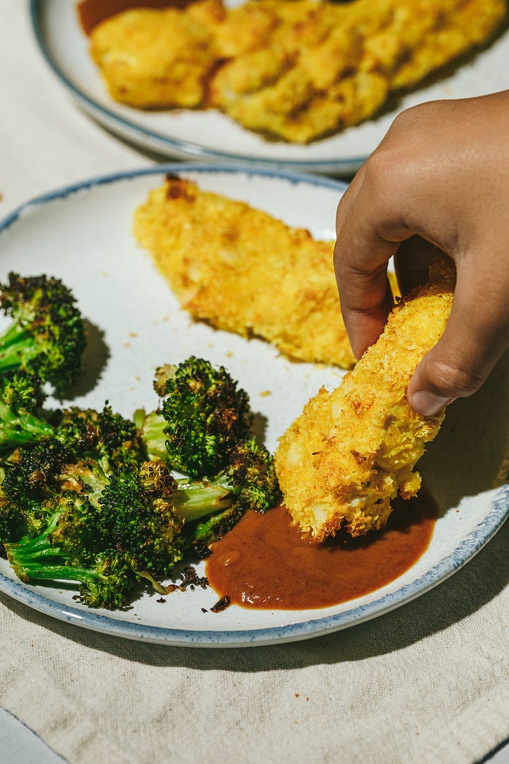 Coconut chicken tenders on baking sheet and on a serving plate. 