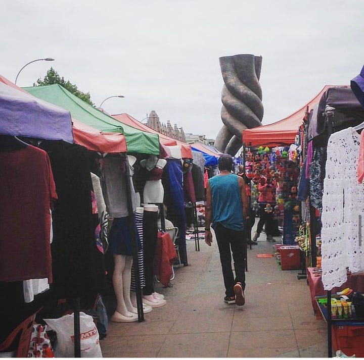 A man walks though the Calle Argentina Flea market on Sunday with a backdrop of a metal spire. The Dissedents Cemetery is perched on a hill overlooking the 