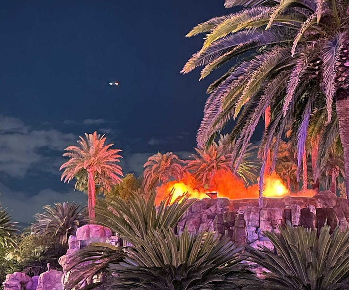 Exterior of Mirage Hotel tower and image of volcano feature erupting on Vegas strip.