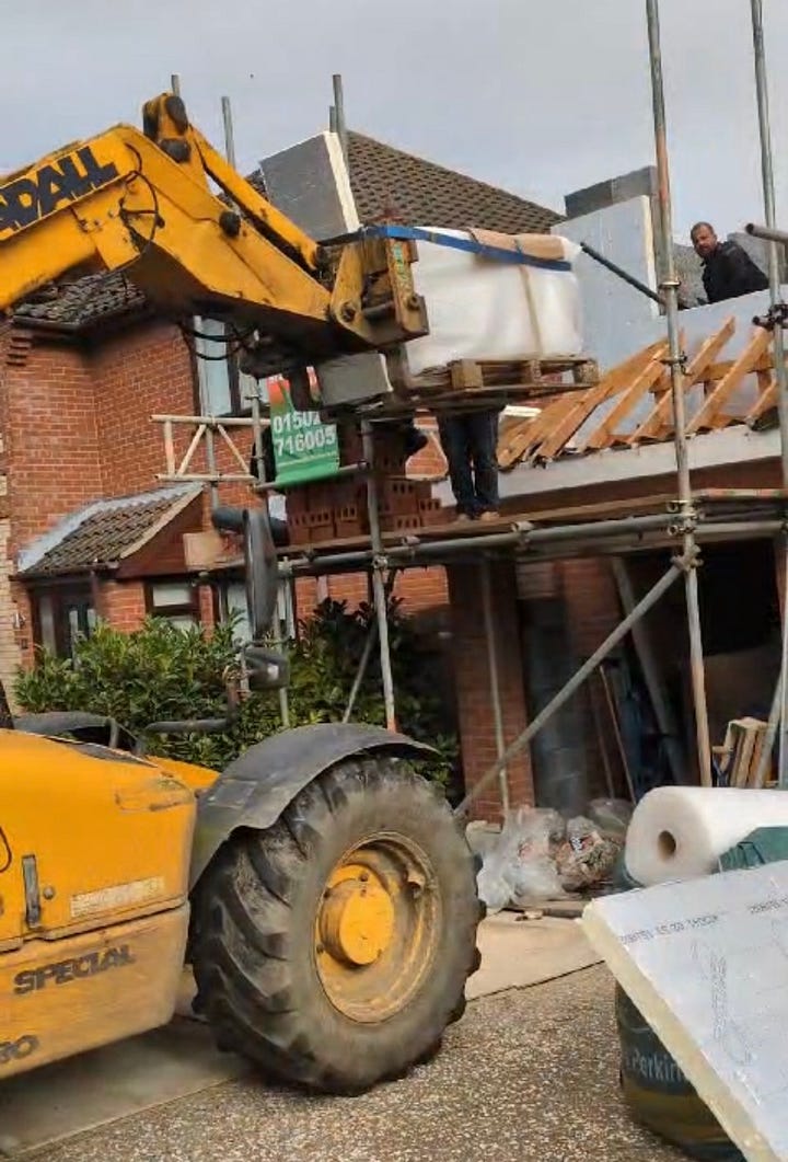 process of lifting a stone bath into an extension using a JCB telehandler