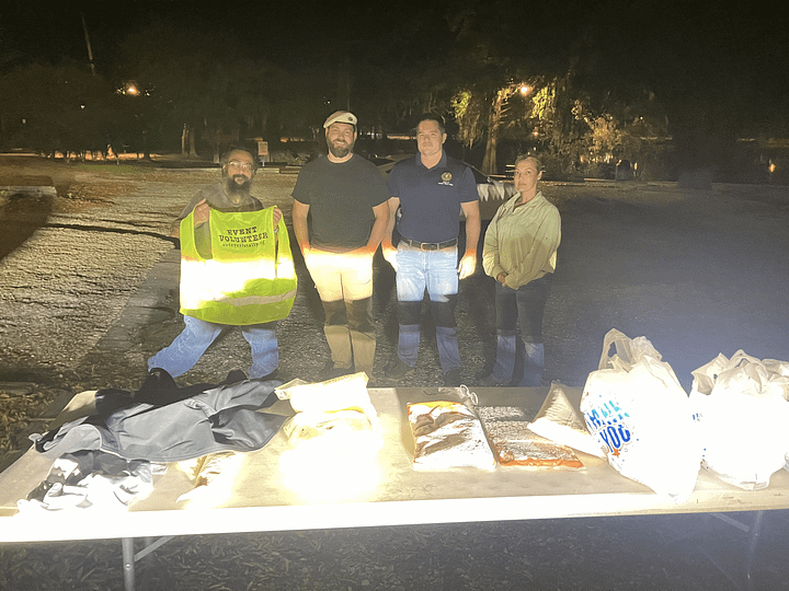 Jon Pantoja, Edward Hood, Daniel Paasch, and Ginni Stalker stand in front of their food distribution tables