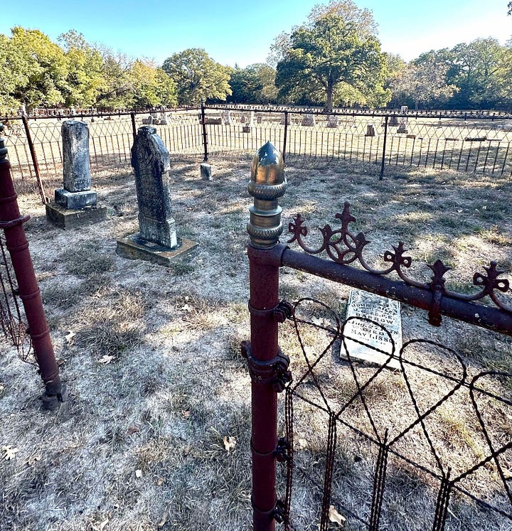 On the left, several headstones inside a wrought iron fence. On the right, rocks and headstones within a wooden fence. 