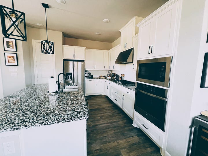 Kitchen with white cupboard doors and marble counter tops.