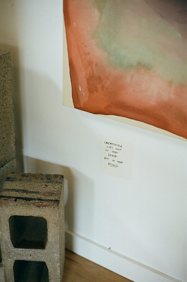 a quote about creativity under an original painting; a cork board pinned with paint swatches and tubes of acrylic paint