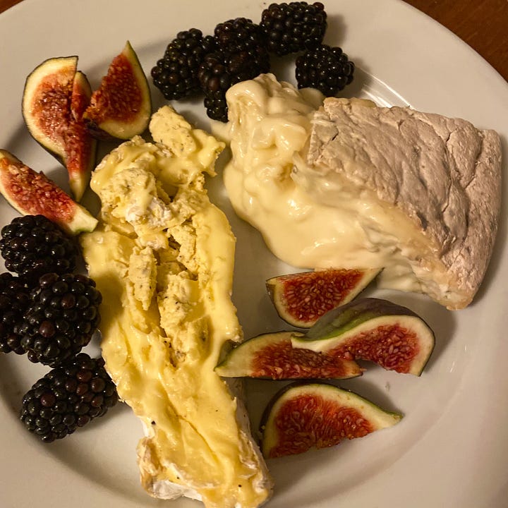 Selections of whole & sliced cheeses, some hard, some squidgy, some very ripe with ripe figs, blackberries and grapes