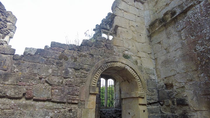 Four photos. A: Carved stone column inside the front door. B: A stone staircase from the courtyard with a carved surround. C: More ornate work carved into the arch of a doorway. D: A column with a finely carved capital found on the upper floor.