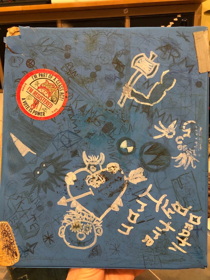 A blue, vinyl-covered 3-ring binder with drawings and skateboarding stickers