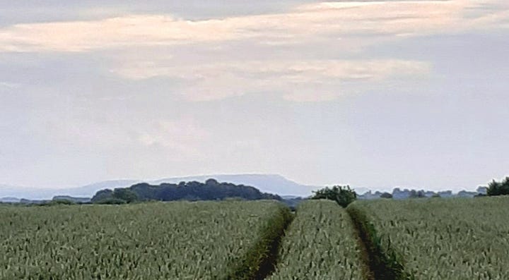 Two images of a distant hill, rising above the countryside