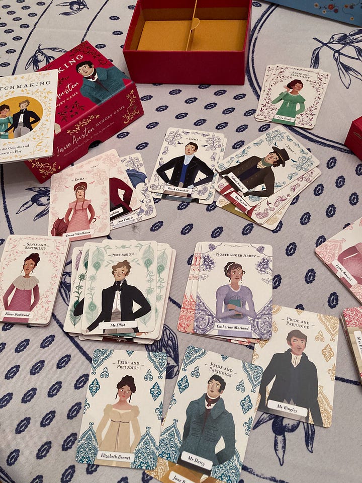 The boxes for "The Jane Austen Game," "The World of Jane Austen" puzzle, "Matchmaking: A Jane Austen Memory Game," and "Jane Austen Playing Cards." Image 2: The game board during a round of play for "The Jane Austen Game." The many pieces are assembled on the board. Image 3: The Emma Woodhouse character board and character cards during a round of play of "The Jane Austen Game." Image 4: Cards from both "Matchmaking: A Jane Austen Memory Game" and "Jane Austen Playing Cards" are spread out on a table next to "The Jane Austen Game" and "The World of Jane Austen" puzzle. Image 5: A close up of the cards from "Matchmaking: A Jane Austen Memory Game" 