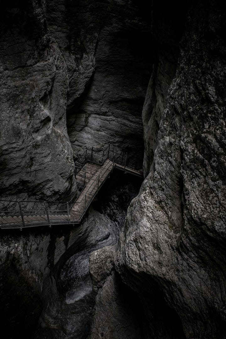 Wooden stairs leading into a deep, dark cave. Cut rocks around a huge mine opening in Spain. Photos by Dario Brönnimann, Jordi Vich Navarro Unsplash