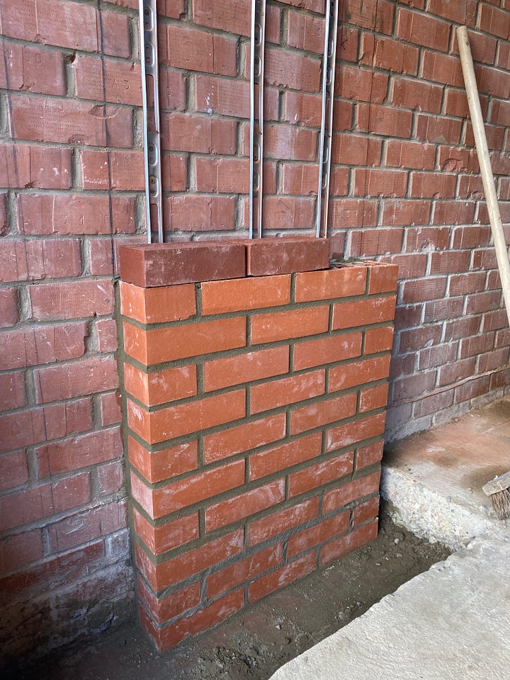 brick pillars being built and blocks being removed from the existing wall