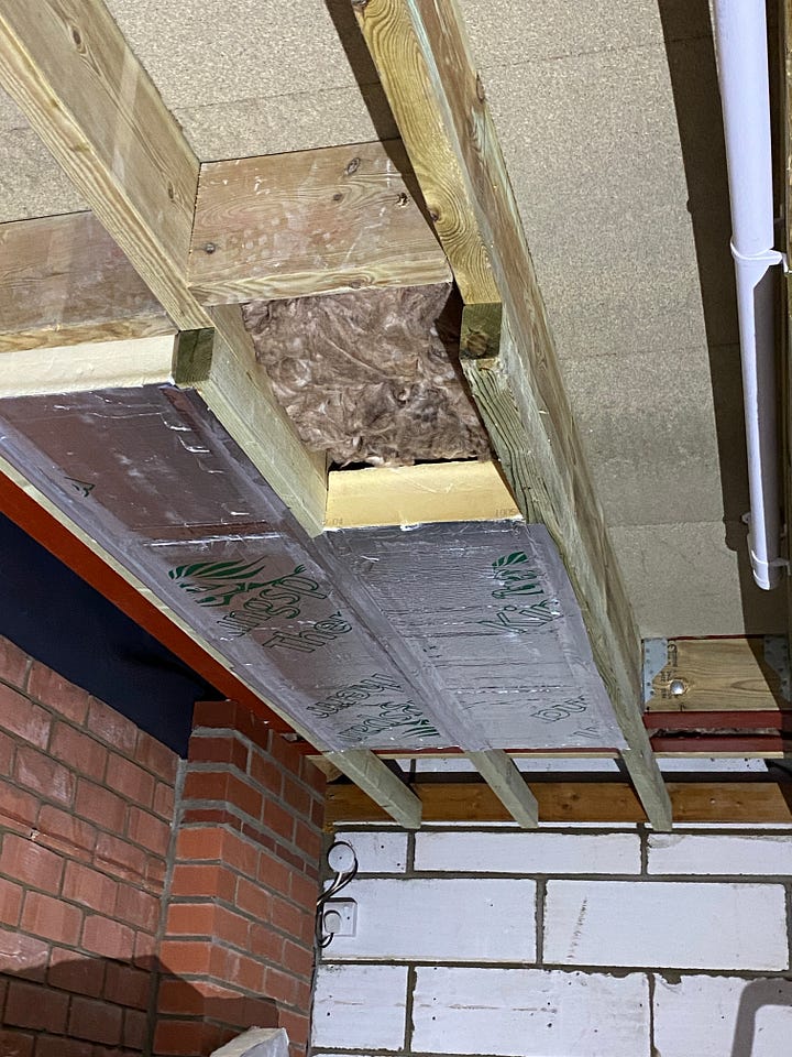 garage ceiling with sheets of insulation being applied into the gaps