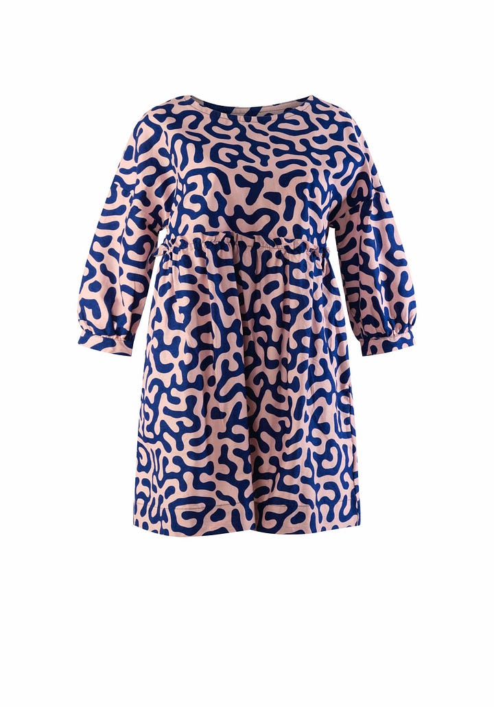 A pink smock dress with a blue geometric design and a pair of white and gold dangle earrings