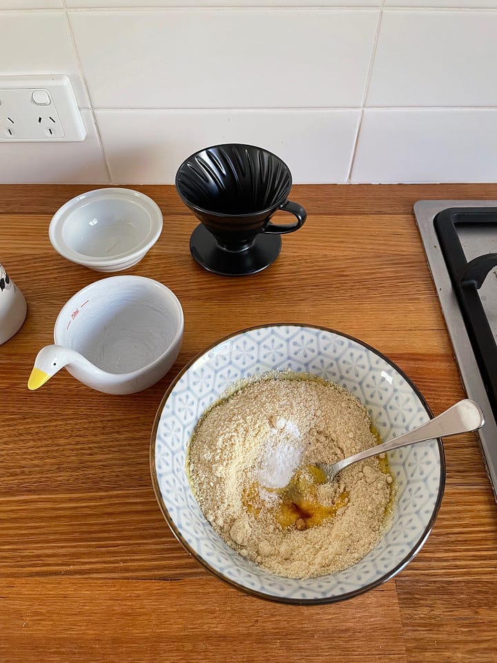 First image shows a ramen bowl with pancake ingredients like almond meal, an egg and vanilla extra. Second image is three pancakes on a speckled plate, topped with yoghurt and stewed plum, a cappuccino nearby.