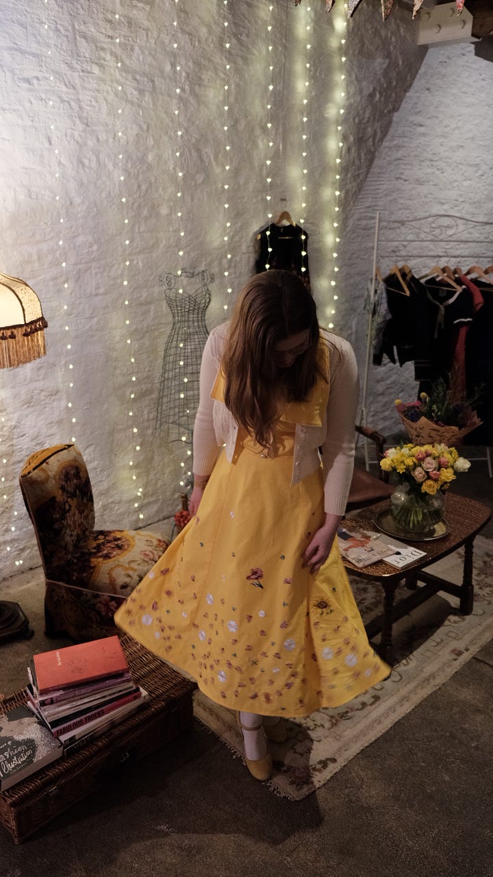 Libby wearing a vintage-style yellow dress decorated in colourful embroidered flowers