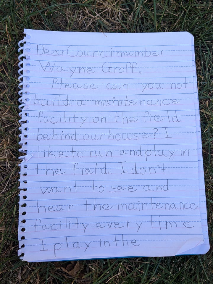 A letter written in pencil on notebook paper. The letter reads: Dear Councilmember Wayne Groff, Please can you not build a maintenance facility on the field behind our house? I like to run and play in the field. I don't want to see and hear the maintenance facility every time I play in the backyard. Thank you for listening. From, [named blurred]