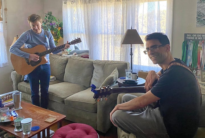 Titus and Mark holding guitars and talking